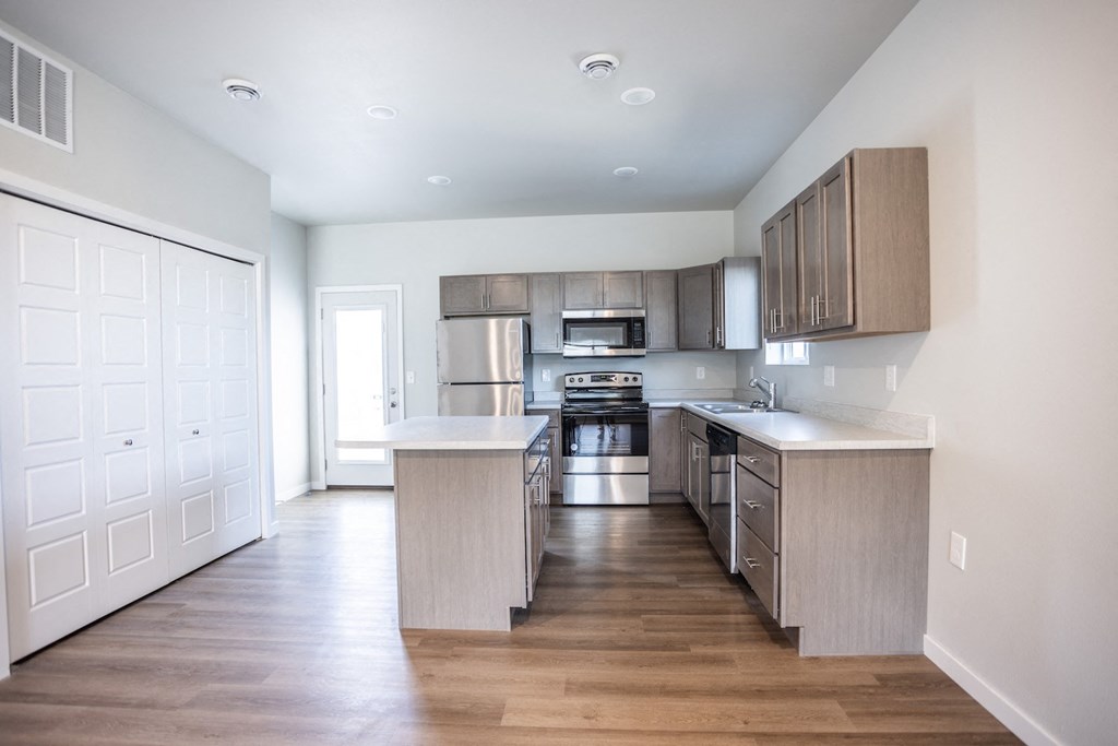 an empty kitchen with wooden floors and stainless steel appliances