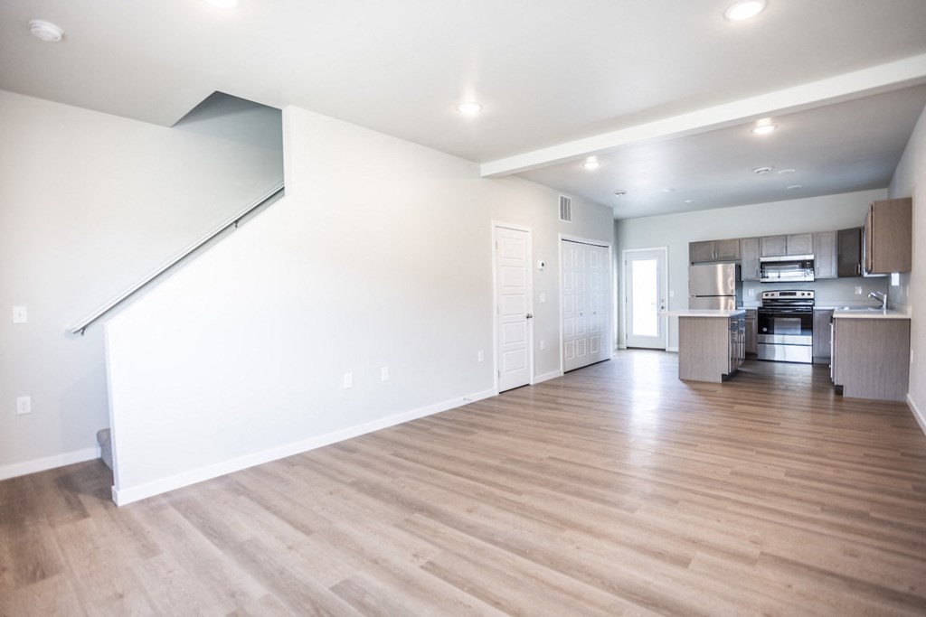 the living room and kitchen of a new home with white walls and wood floors