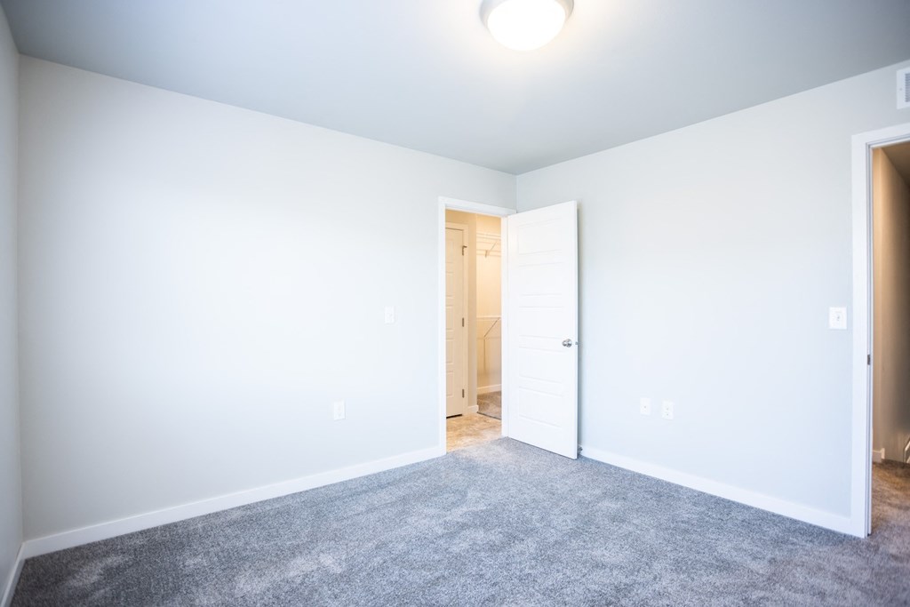 a room with a carpeted floor and a door to a closet