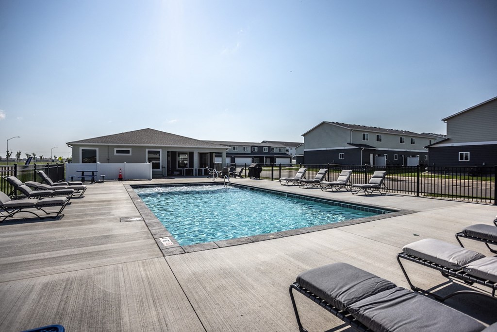 a pool with lounge chairs and a house in the background