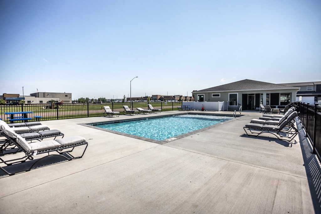 a pool with lounge chairs and a house in the background