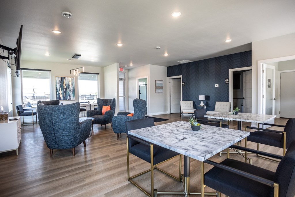 a communal area with tables and chairs and a kitchen and living room