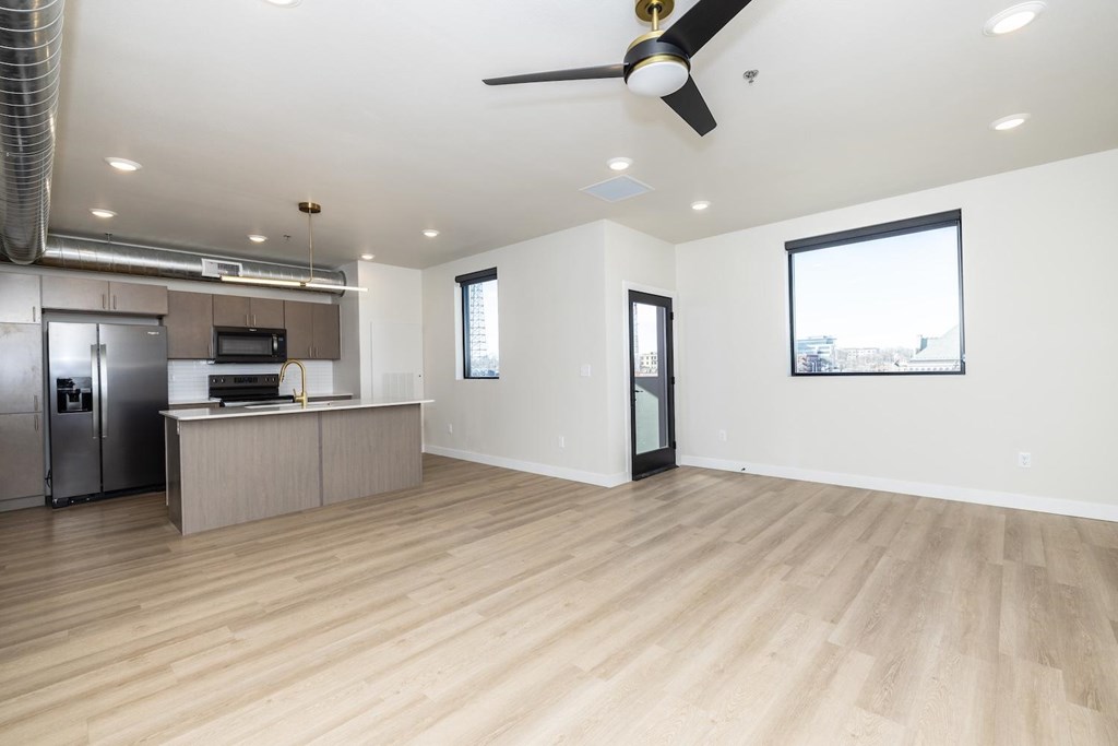 A spacious kitchen with a refrigerator, microwave, and a ceiling fan.