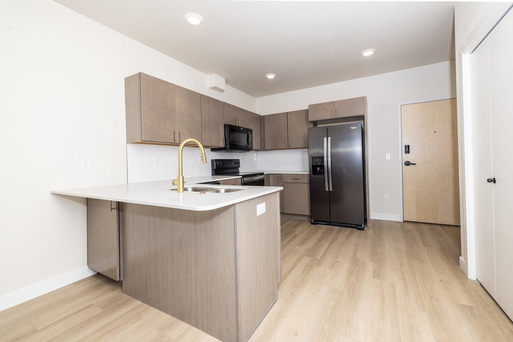A kitchen with a refrigerator, microwave, and oven.