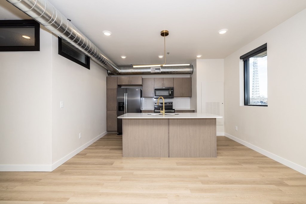 A modern kitchen with wooden floors and stainless steel appliances.