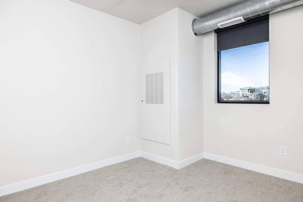 A room with a window and a picture on the wall.