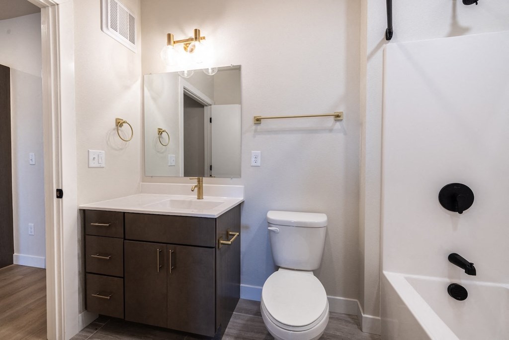 A white toilet sits in a bathroom next to a sink and a bathtub.