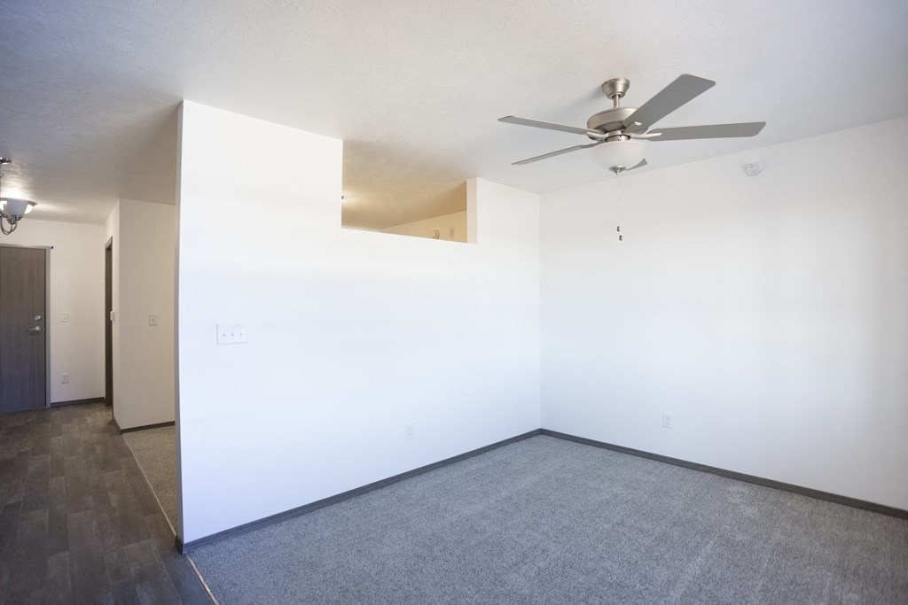 an empty living room with white walls and a ceiling fan