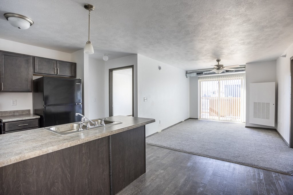 an empty living room with a kitchen and a sliding glass door