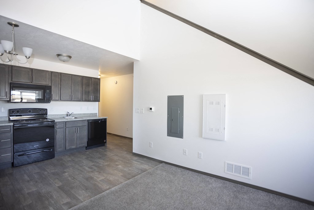 an empty kitchen and living room with black appliances and white walls