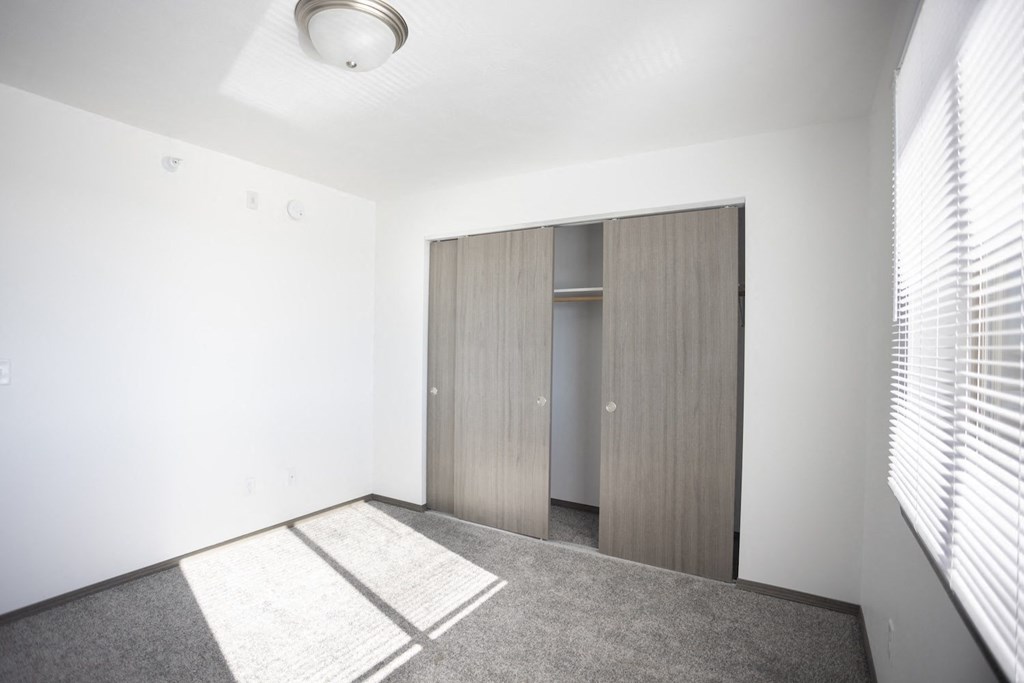 an empty living room with white walls and grey carpet