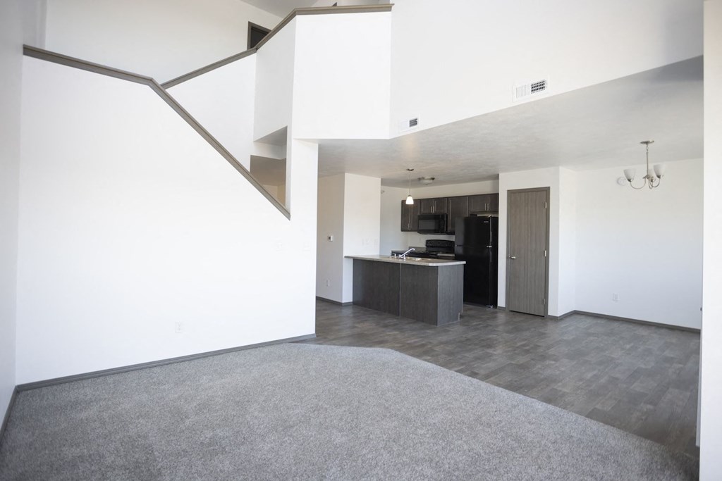 an empty living room and kitchen with white walls and concrete floors