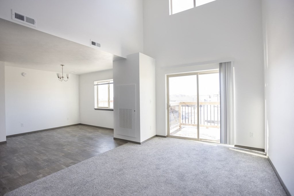 an empty living room with a sliding glass door to a balcony