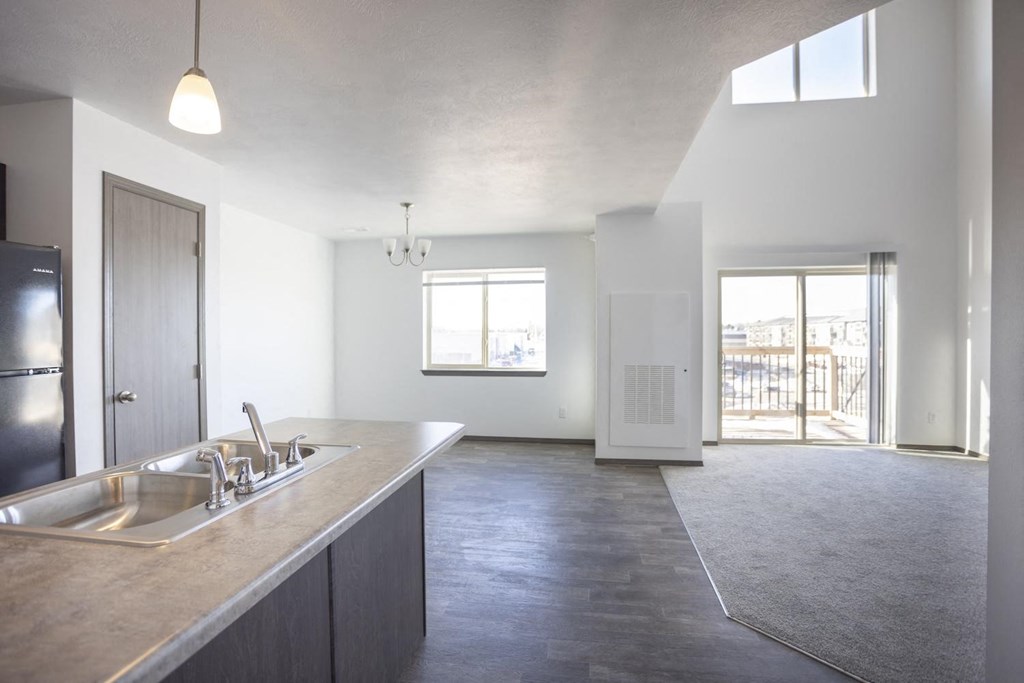 an empty kitchen and living room with a sink and refrigerator