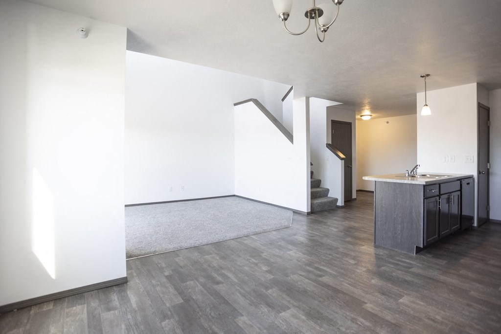 the living room and kitchen of a new home with white walls and wood flooring
