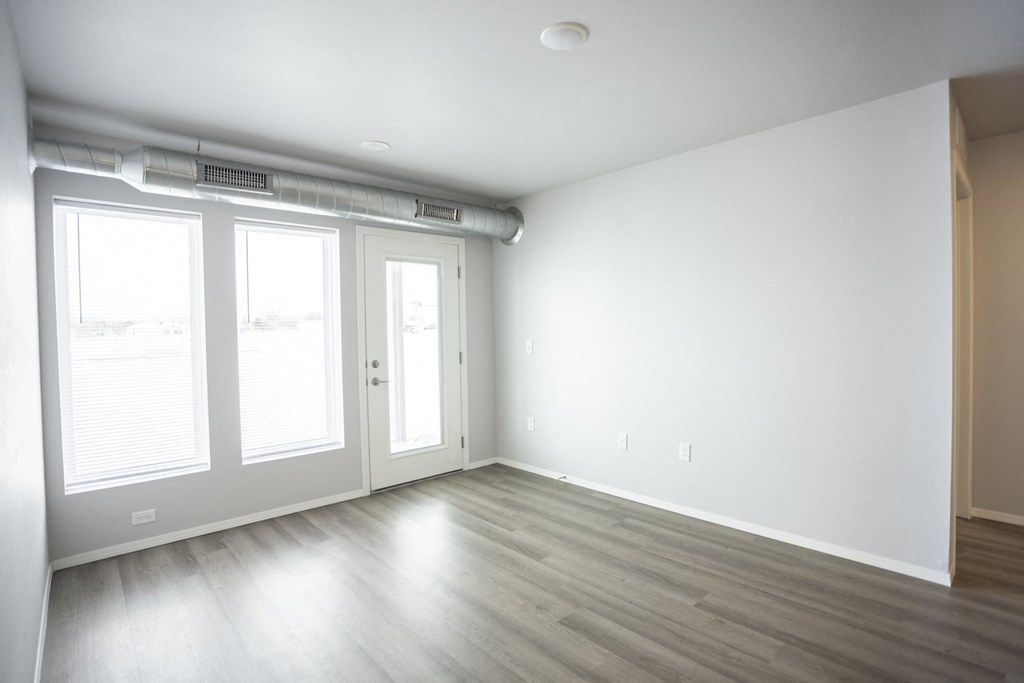 Empty living room with large, bright windows.