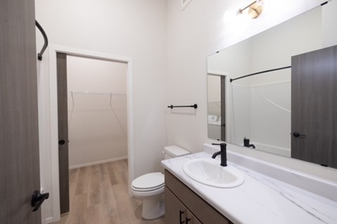 A bathroom with a toilet, sink, and mirror.