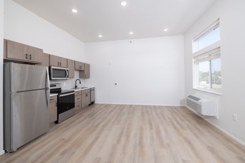 A kitchen with a refrigerator, microwave, oven, and cabinets.