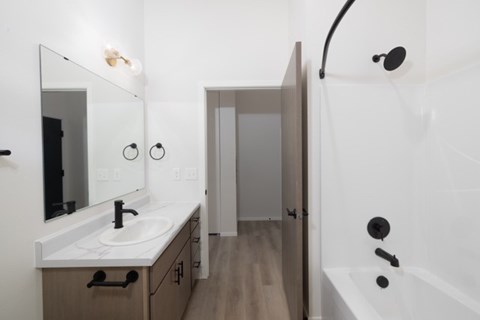 A bathroom with a sink, mirror, and bathtub.
