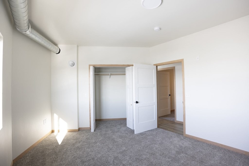 a bedroom with a door to a closet and a carpeted floor
