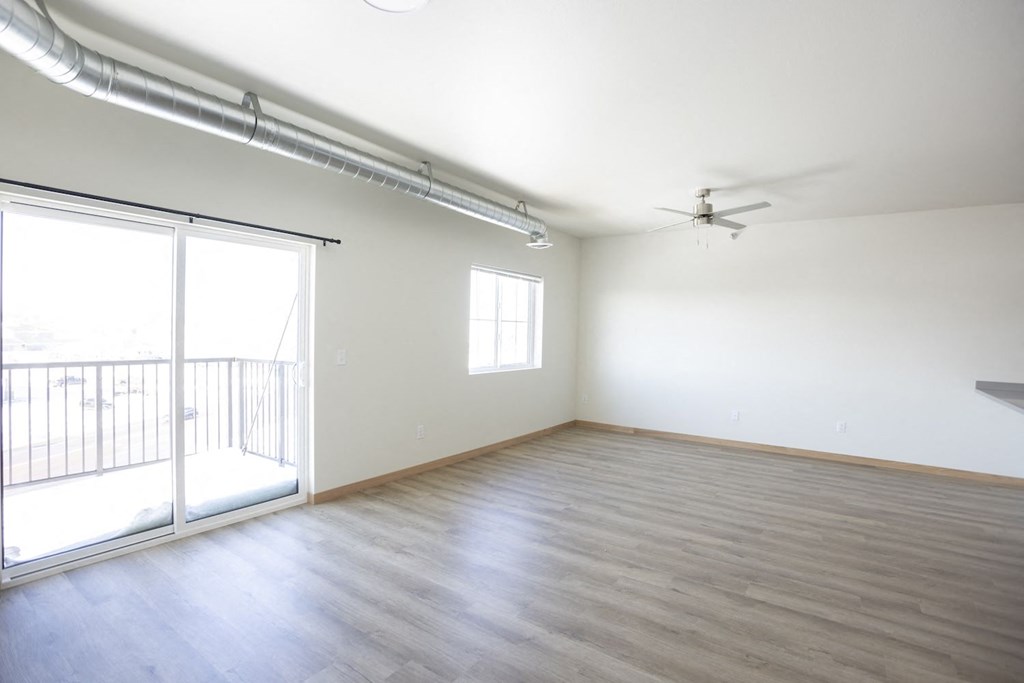 an empty living room with a sliding glass door to a balcony