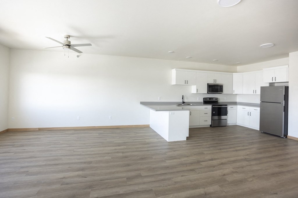 an empty kitchen with white cabinets and a stainless steel refrigerator