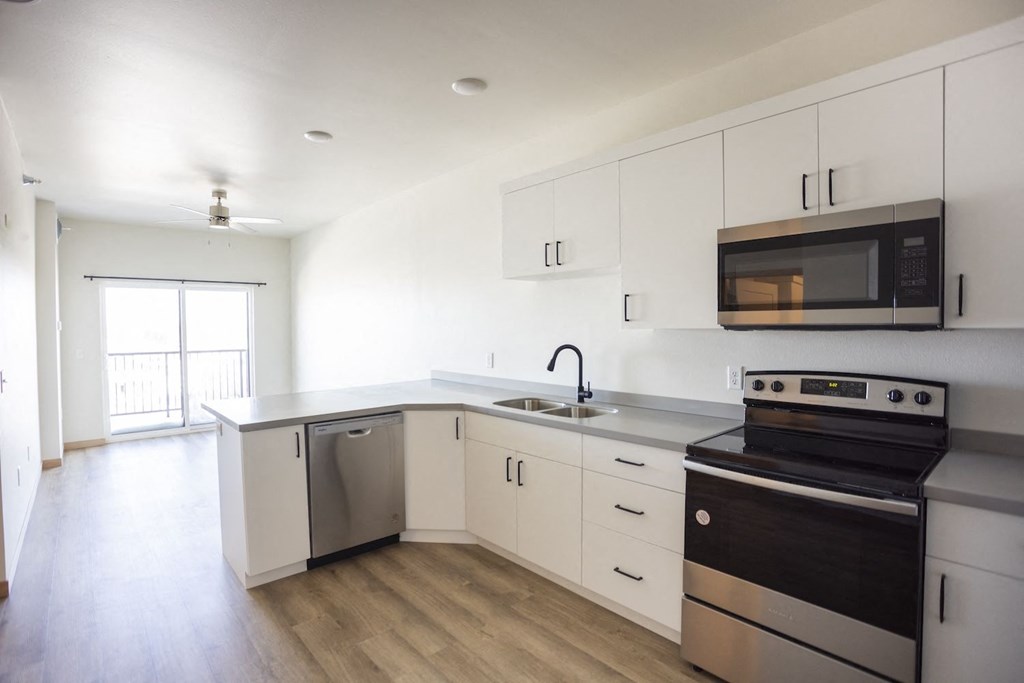 an empty kitchen with white cabinets and stainless steel appliances