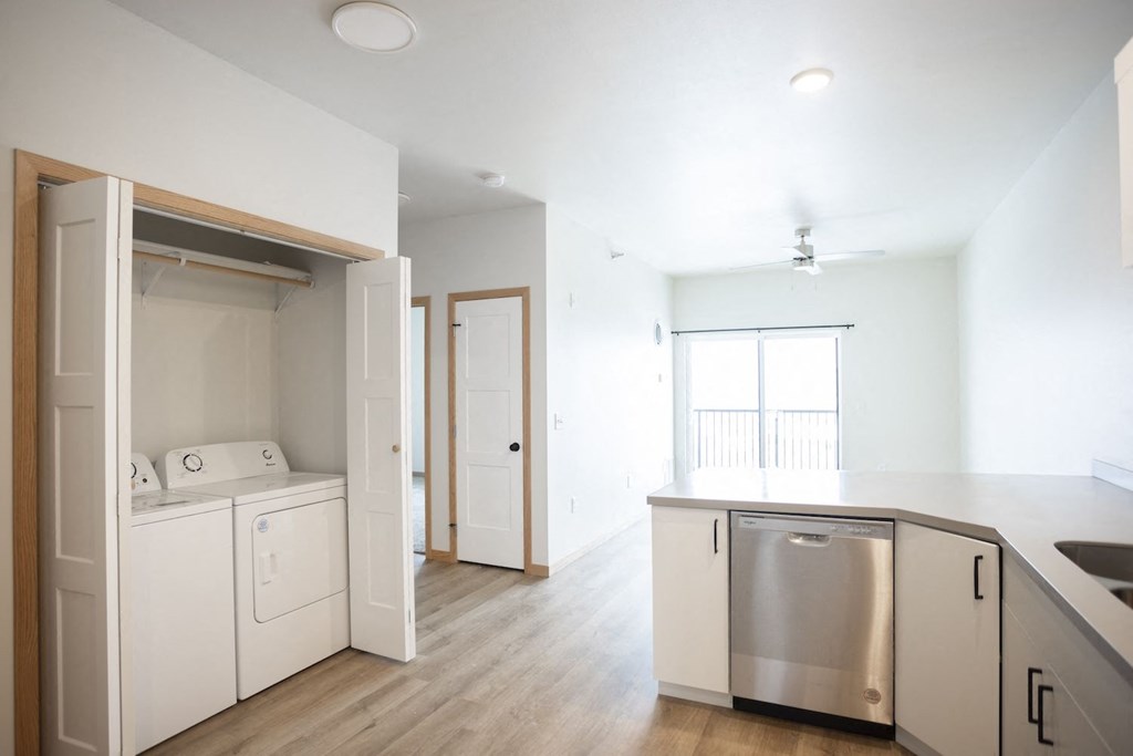 an empty kitchen and laundry room with white walls and wood floors