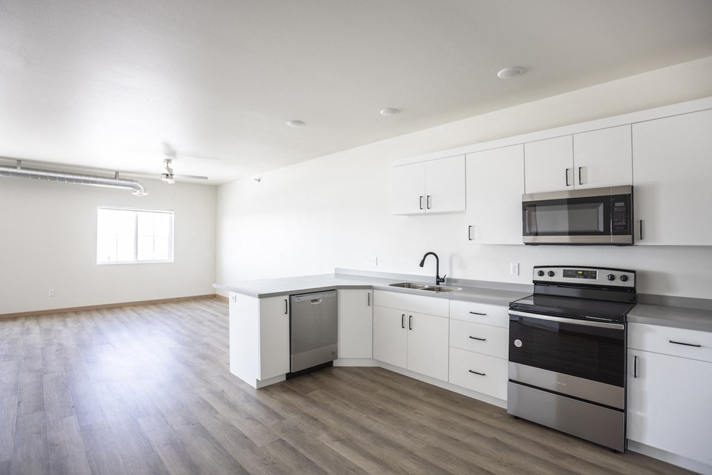 an empty kitchen with white cabinets and stainless steel appliances