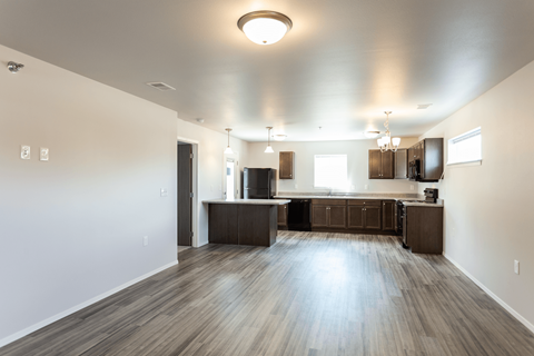 an empty kitchen and living room with wood floors and white walls