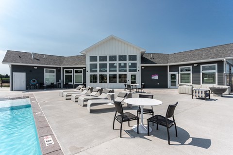 a pool with chairs and tables in front of a building