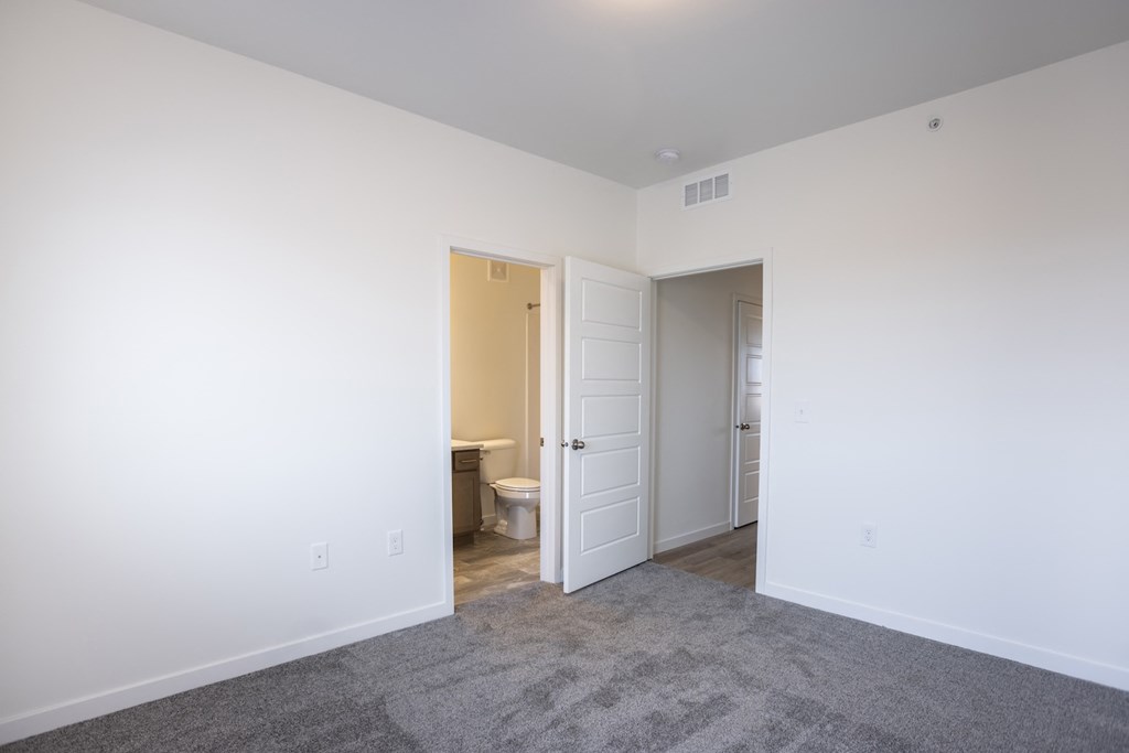 an empty room with a door to a bathroom and a toilet
