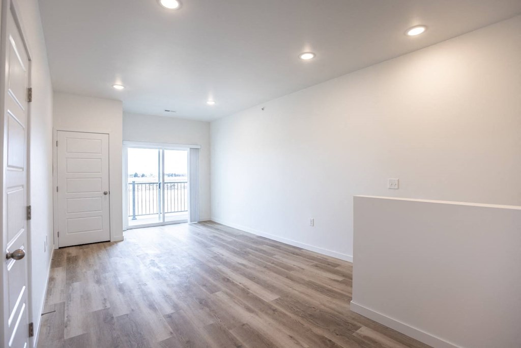 a living room with white walls and a door to a balcony