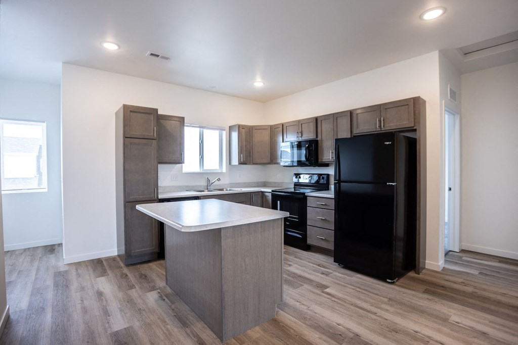 a kitchen with a large island and a black refrigerator