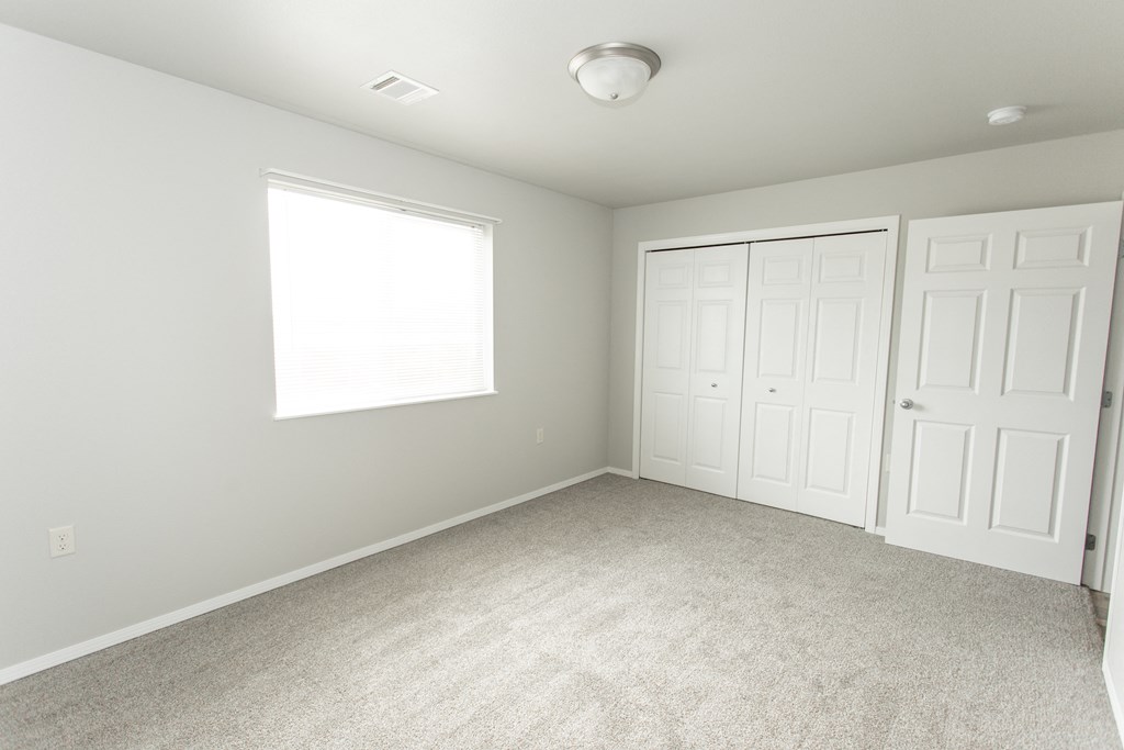 an empty bedroom with two closets and a window