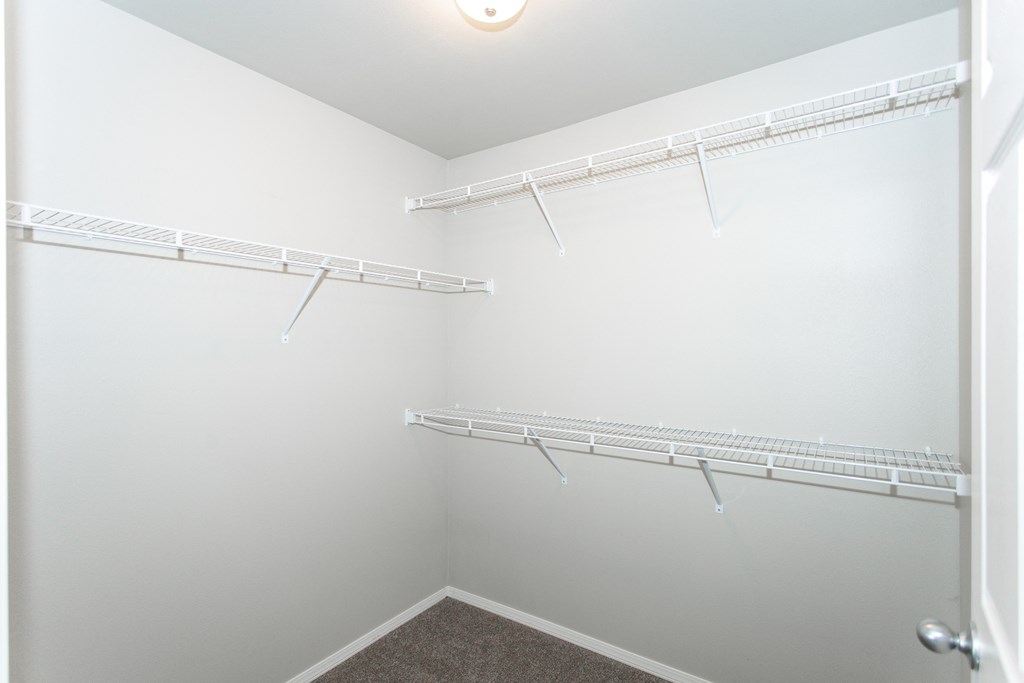 a spacious walk in closet with hanging racks and a door to the bathroom