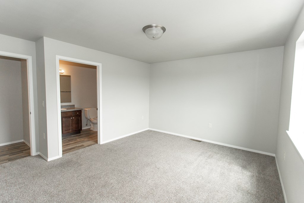 an empty room with white carpet and a bathroom
