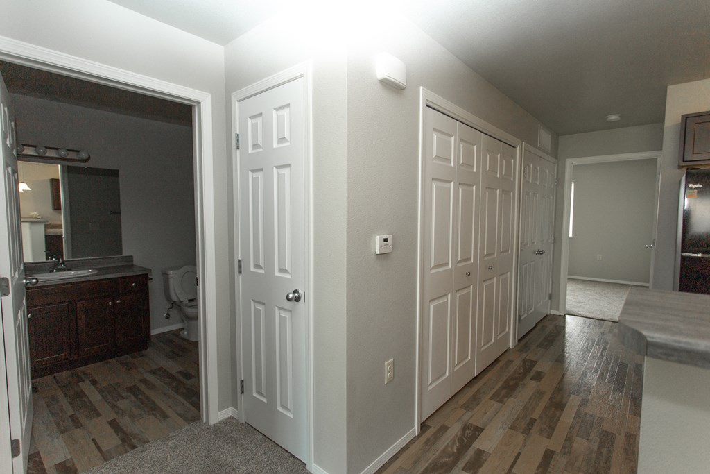 a view of a hallway with three doors and a bathroom