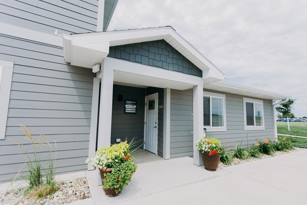 the front of a gray house with a porch and a door