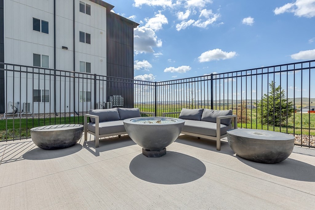 an outdoor patio with couches and tables and a building in the background