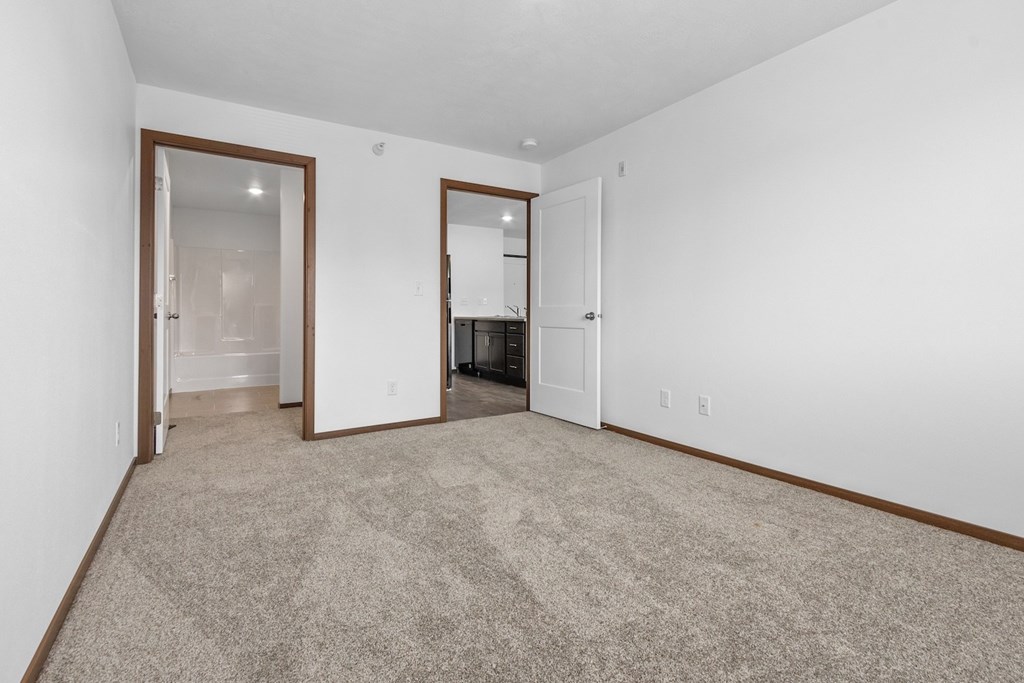 A room with a carpeted floor and two open doors.