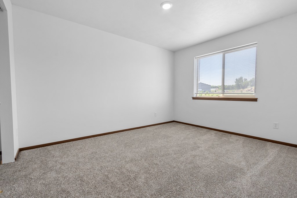 A room with a carpeted floor and a window.