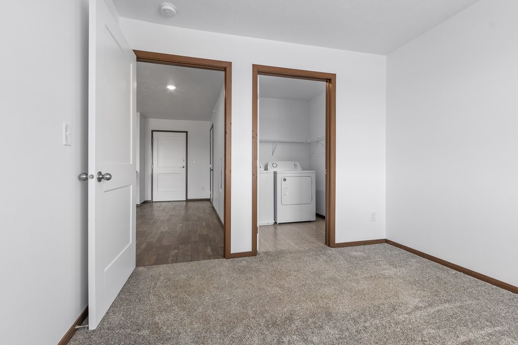 A white room with a brown door and a brown carpet.