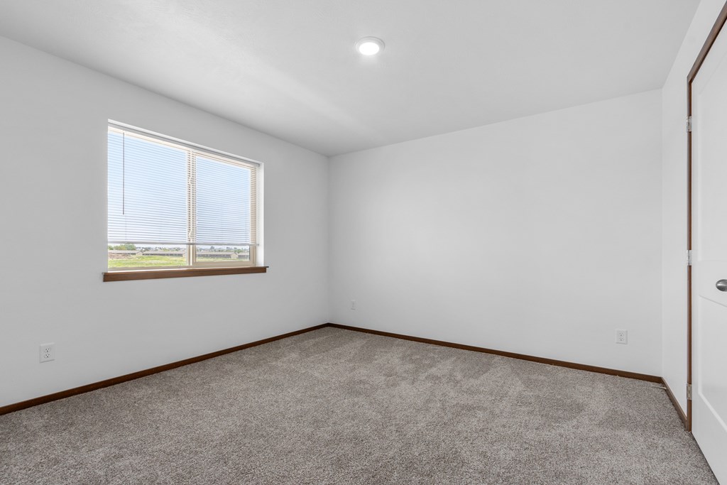 A room with a carpeted floor and a window.