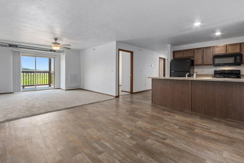 A spacious living room with wooden flooring and modern appliances in the kitchen.
