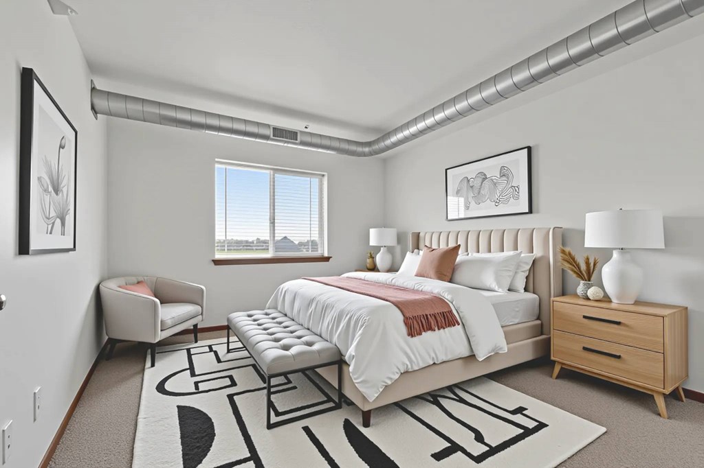 A bedroom with a large bed, a bench, and a rug with a black and white design.