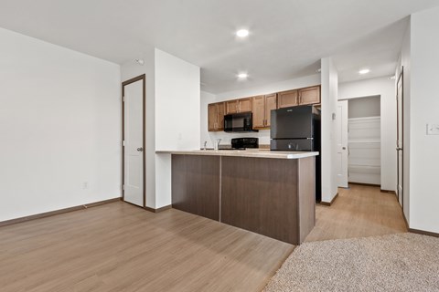 A kitchen with a black fridge and microwave, and a brown island.