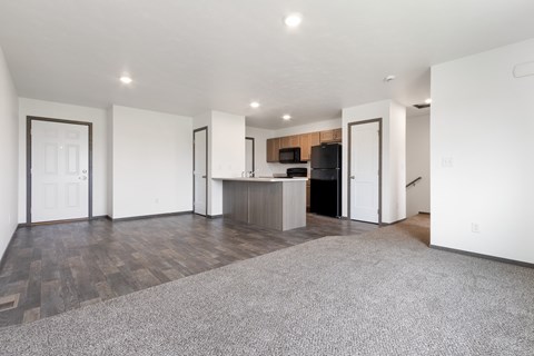 A spacious living room with a kitchen in the background.