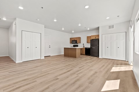 A spacious room with wooden flooring and white walls.