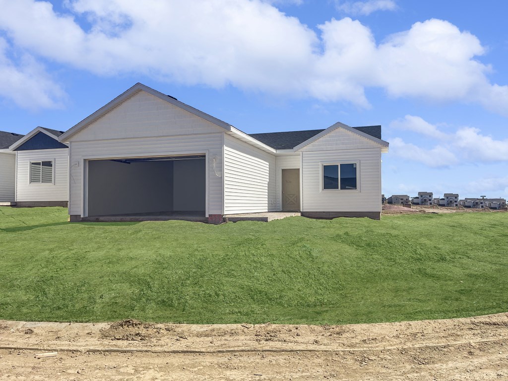 a house with a garage on a grassy hill